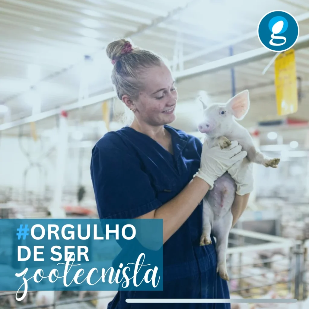 Zootecnista segurando um leitão recém-nascido dentro de uma granja de suínos, vestindo uniforme profissional azul e luvas, com expressão de cuidado e dedicação. Post da GENEPRO em homenagem ao Dia do Zootecnista com a hashtag #OrgulhoDeSerZootecnista.