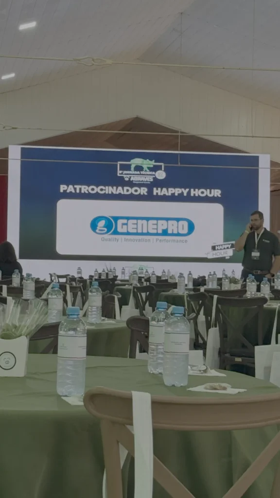 Telão com logotipo da Genepro como Patrocinador Happy Hour na 9ª Jornada Técnica Abraves GO 2026, com salão de evento preparado para recepção dos participantes da suinocultura.